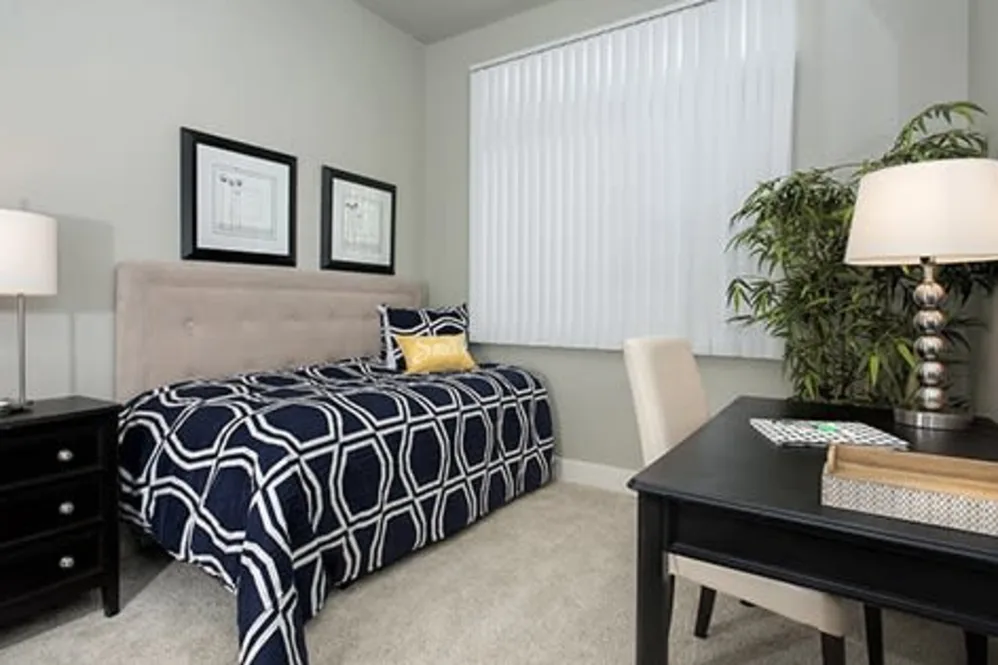 Furnished single bedroom with navy geometric bedding and study desk in a renovated student apartment near UC Davis