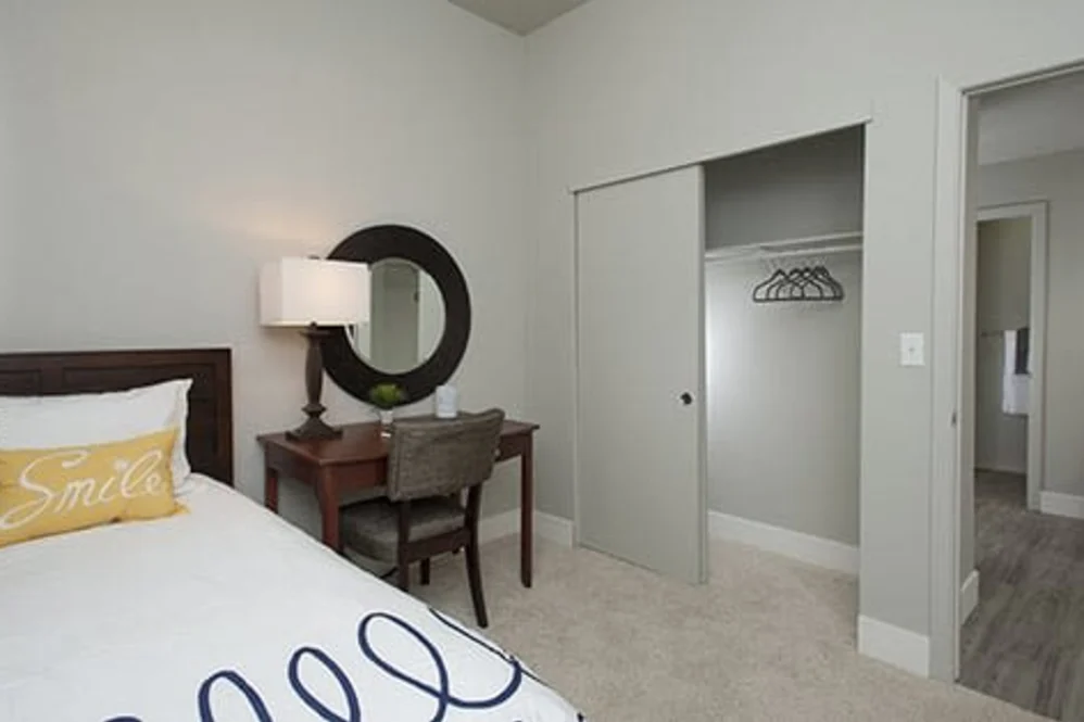 Bedroom with bed, desk, round mirror and sliding closet in a renovated apartment