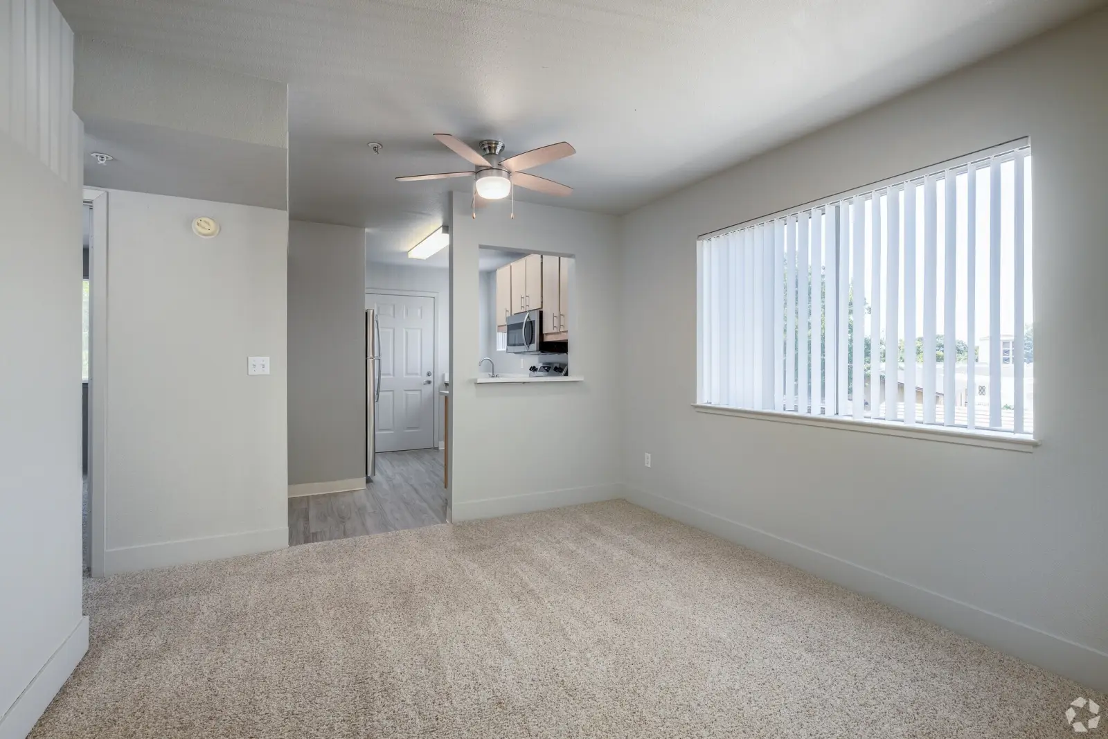 Dining area with ceiling fan, carpeted floor and pass-through to kitchen at Octave Davis apartment