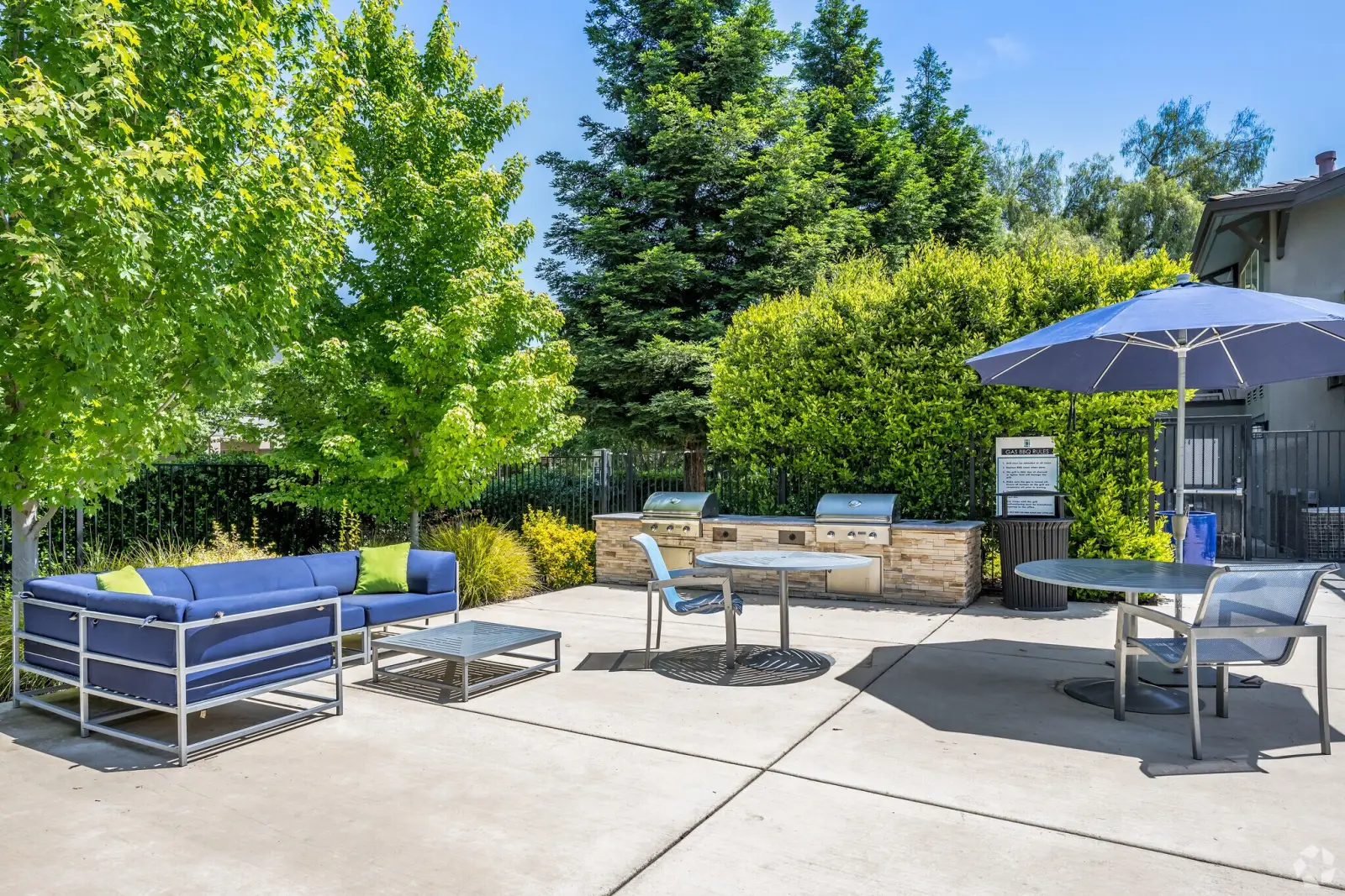 Outdoor grilling and lounge area with blue seating, umbrella, and two built-in gas grills