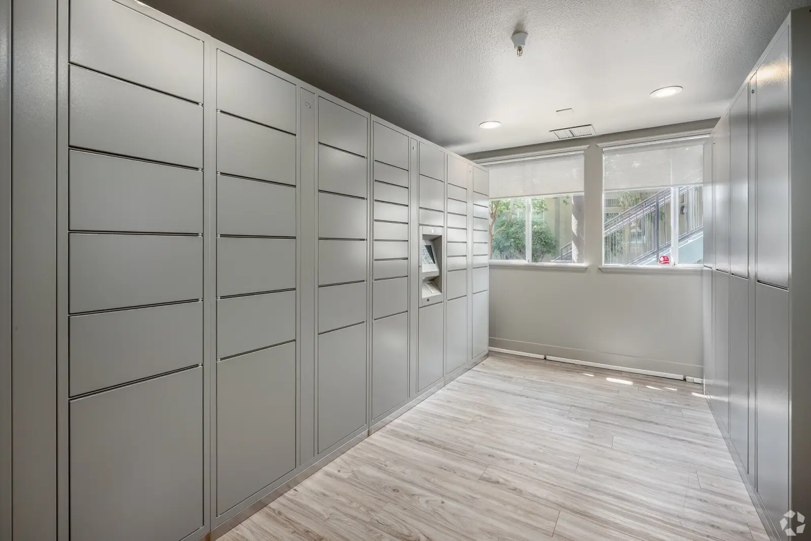Interior package locker room with gray lockers and touchscreen kiosk at student apartments near UC Davis