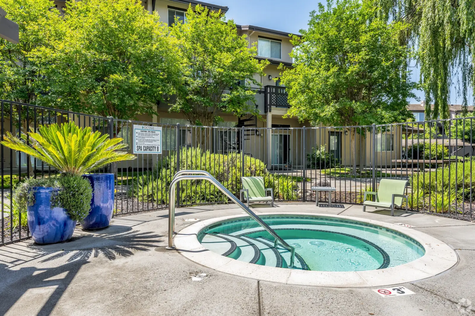 Circular outdoor spa/jacuzzi with handrail and lounge chairs at Octave apartments in Davis, CA