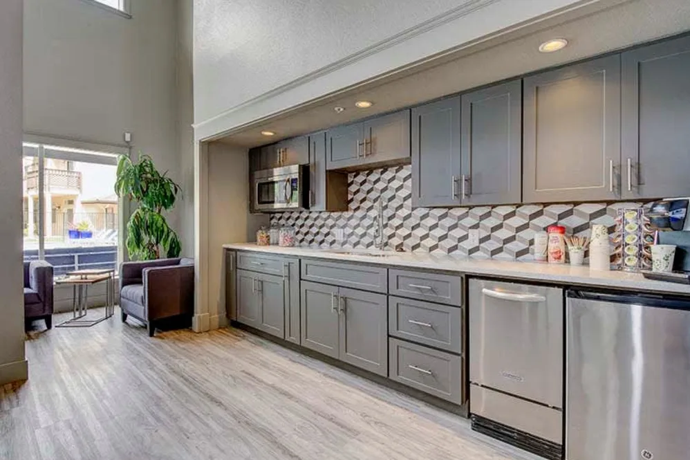 Clubhouse kitchenette with gray cabinets, geometric tile backsplash and lounge seating