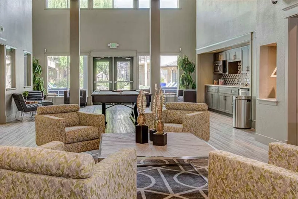 Clubhouse lounge with seating, pool table, and kitchenette at student apartments near UC Davis